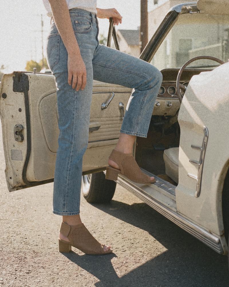 Tan nubuck J.Adams Maddie perforated peep-toe booties stepping into a vintage cream convertible, with straight jeans